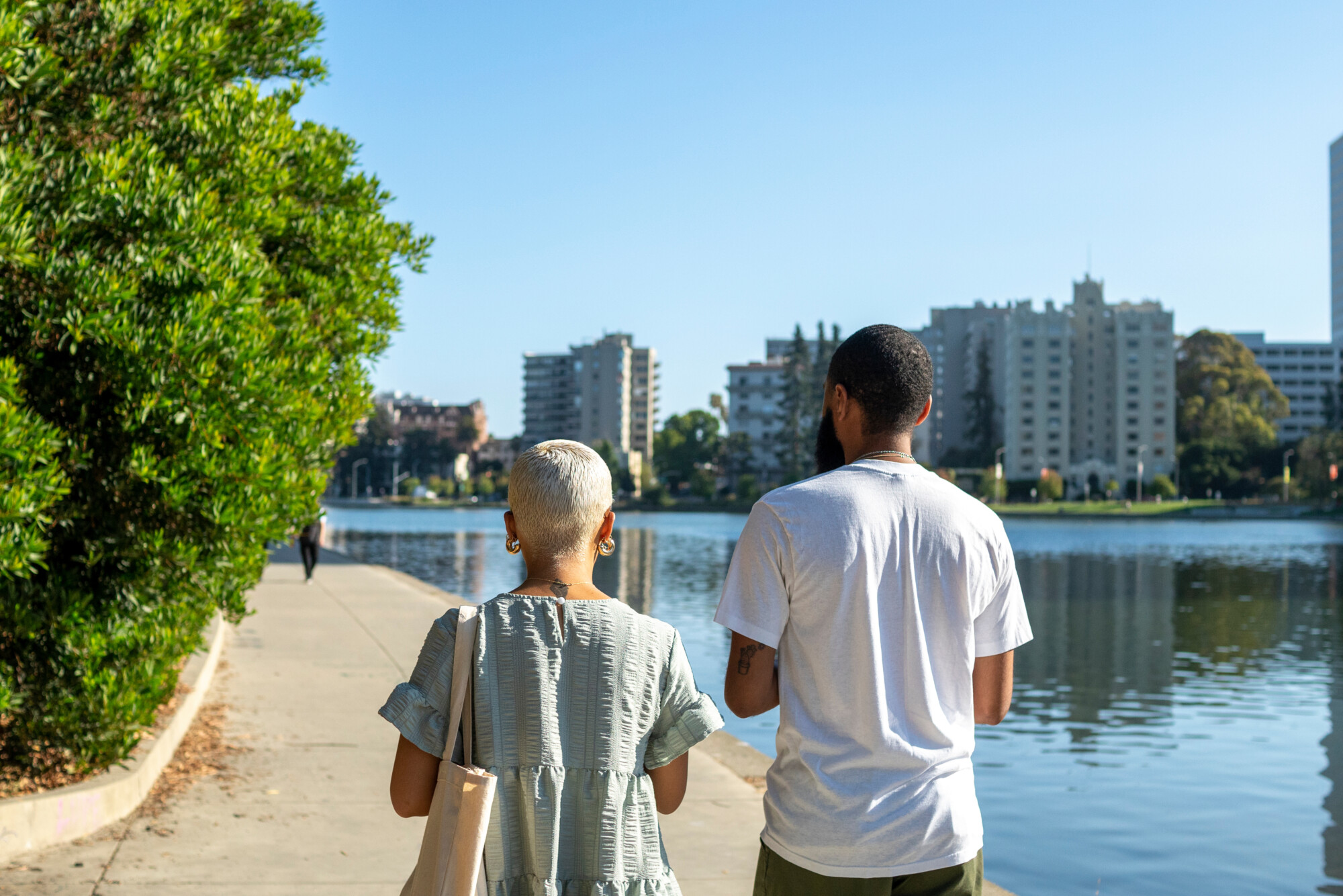 Two people with their backs to the camera walking next to a lake in California